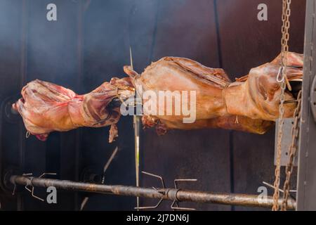 Processo di cottura delle carcasse di ariete su spit al mercato di Street food estivo: Primo piano Foto Stock