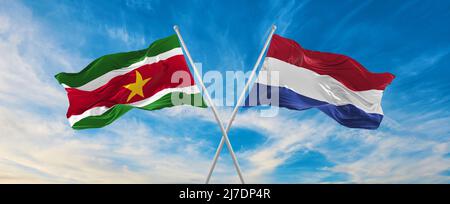 Due bandiere incrociate Suriname e Netherland che ondeggiano in vento a cielo nuvoloso. Concetto di rapporto, dialogo, viaggiare tra due paesi. 3d illustre Foto Stock