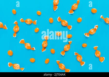 caramelle e dolci arancioni su sfondo blu. assortimento di caramelle. carta da parati per l'uso del testo. Foto Stock