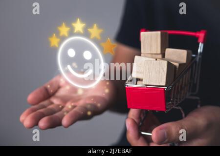 Valutazione e concetto di soddisfazione. Cinque stelle e sorridere emoji che mostra un eccellente supermercato. Primo piano sul carrello. Foto Stock