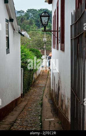 Una stretta stradina acciottolata che collega via Direita e via Ministro Gabriel Passos nel centro storico di Tiradentes sotto il cielo nuvoloso. Foto Stock