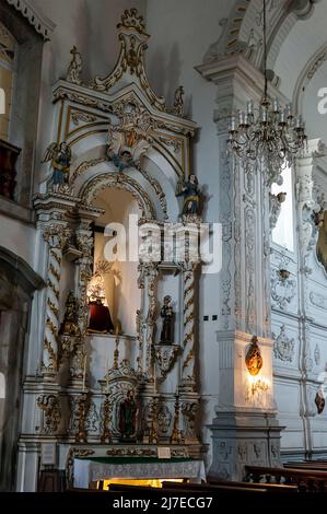 Veduta interna della parrocchia di Nossa Senhora do Carmo con molte immagini religiose attorno ad un piccolo altare ai lati della chiesa. Foto Stock