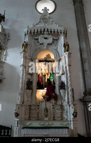 Veduta interna della parrocchia di Nossa Senhora do Carmo con molte immagini religiose attorno ad un piccolo altare ai lati della chiesa. Foto Stock