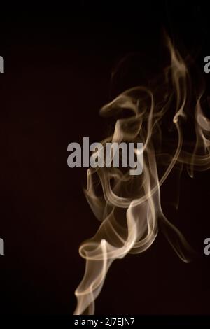 Giallo dorato vorticoso, motivo di fumo ascendente su uno sfondo nero, la foto potrebbe essere usata come sfondo, trama di fumo, astratto, o stock generale Foto Stock