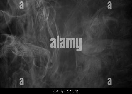 Una foto in bianco e nero di una nuvola di fumo contro uno sfondo nero, la foto potrebbe essere utilizzata come sfondo, trama di fumo o astratto - Fotografia di stock Foto Stock