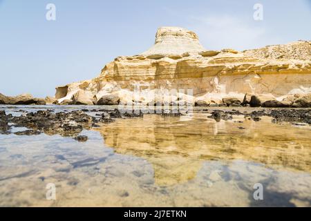 La formazione rocciosa di Xwejni si riflette nelle piscine rocciose a bassa marea sull'isola di Gozo a Malta. Foto Stock