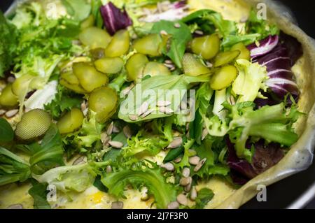 Insalata calda sull'uovo strapazzate sulla padella. Piatto con diverse lattughe, cetriolini e semi di girasoli Foto Stock