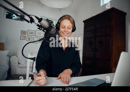 Podcaster femmina caucasico che lavora da casa scrittura script per la registrazione Foto Stock