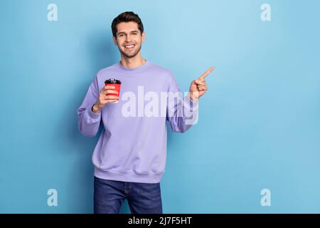 Ritratto di ragazzo attraente bere tè mostrando spazio copia per andare eco-friendly tazza isolato su sfondo di colore blu chiaro Foto Stock