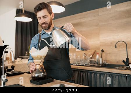 Barista versare l'acqua per preparare il caffè utilizzando il sistema antigoccia manuale Foto Stock