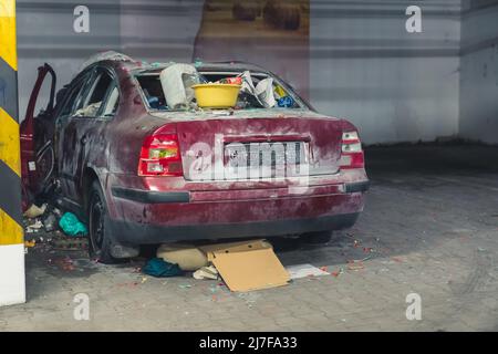 foto di una macchina distrutta con spazzatura nel parcheggio sotterraneo pieno colpo . Foto di alta qualità Foto Stock