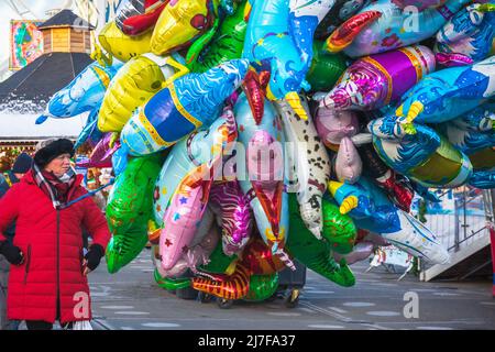 Londra, UK - 28 Novembre, 2021 - il venditore di strada femminile vende i palloncini multipli dell'elio del carattere del cartone animato al funfair di Natale Hyde Park Winter Wonderlan Foto Stock