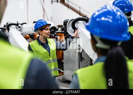 Team di ingegneri che lavorano in fabbrica robotica - concetto di industria tecnologica Foto Stock