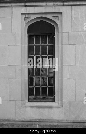 Finestre gotiche medievali con vetri su un muro di pietra in bianco e nero. Foto Stock