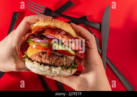 Cheeseburger fresco con lattuga, cetriolo, pomodoro, cipolla e pancetta su sfondo rosso vibrante Foto Stock