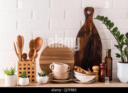 articoli ecologici di stoviglie moderne sul piano di lavoro in legno della cucina contro il muro di mattoni bianchi. materiali ecologici senza plastica Foto Stock