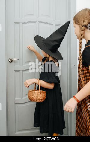 Ragazza amici in costumi di Halloween che bussano alla porta, trucco o trattare. I suoi occhi chiusi, raccogliendo il suo coraggio. Foto Stock