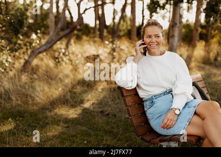 Donna sorridente sul banco di lavoro che parla per telefono Foto Stock