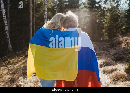 Vista posteriore delle donne avvolte con bandiere ucraine e russe Foto Stock