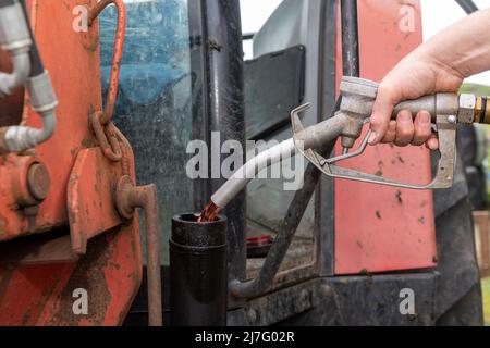 Farmer che riempie il trattore con diesel rosso in un'azienda agricola, North Yorkshire, Regno Unito. Foto Stock
