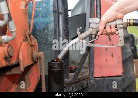 Farmer che riempie il trattore con diesel rosso in un'azienda agricola, North Yorkshire, Regno Unito. Foto Stock