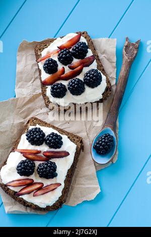 Sandwich con formaggio dolce e frutti di bosco su sfondo di legno blu Foto Stock