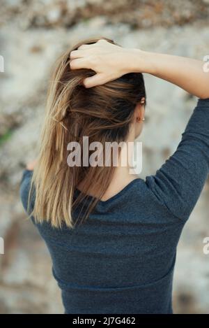 Vista posteriore delle mani della donna nei capelli Foto Stock