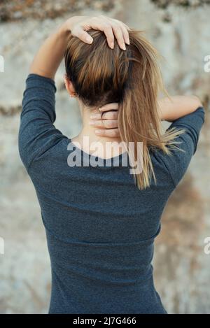 Vista posteriore delle mani della donna nei capelli Foto Stock