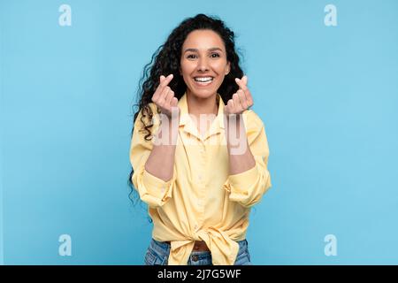 Sorridente giovane donna che fa il dito coreano mini cuore gesto Foto Stock