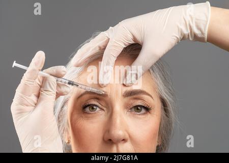 Ringiovanimento della pelle maturo. Ritratto closeup della donna anziana che riceve il trattamento cosmetico con iniezione di bellezza Foto Stock