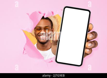 Il ragazzo nero mostra lo schermo bianco vuoto dello smartphone attraverso la carta strappata Foto Stock