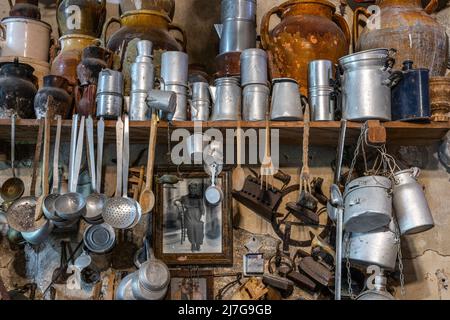 Mostra museale di utensili per la casa, pentole, padelle, anfore e ferri da stiro, antichi o vintage appesi al muro. Peschici, provincia di Foggia, Puglia Foto Stock