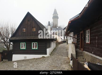 Štramberská Trúba (Torre di Štramberk) si eleva sulle tradizionali case di legno (roubenka) nella pittoresca città di Štramberk nella regione moravo-silesiana della Repubblica Ceca. Foto Stock