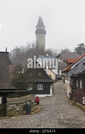 Štramberská Trúba (Torre di Štramberk) si eleva sulle tradizionali case di legno (roubenka) nella pittoresca città di Štramberk nella regione moravo-silesiana della Repubblica Ceca. Foto Stock