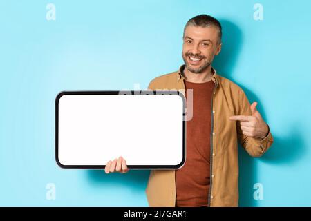 Joyful Man Holding Big Mobile Phone che mostra schermo, sfondo blu Foto Stock