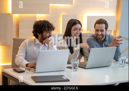 Gruppo di tre dipendenti seduti nella sala riunioni Foto Stock