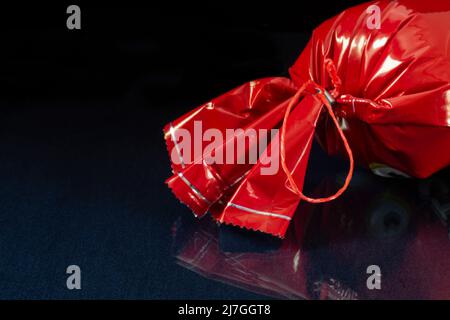 Caramelle in un involucro luminoso sul tavolo. Cibo su sfondo nero Foto Stock