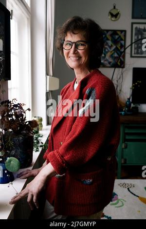 Donna sorridente che indossa occhiali in piedi vicino a piante a casa Foto Stock