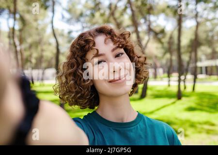 Giovane bella donna rossa scattando foto selfie. Scattare foto autoritratto selfie. Foto Stock