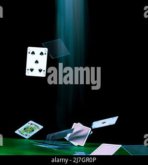 Carte da gioco che cadono al rallentatore su un tavolo con tracce di movimento sfocate, con spazio per la copia di un poster, su sfondo nero. Foto Stock