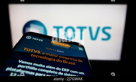 Smartphone con pagina web della società software brasiliana TOTVS S.A. sullo schermo di fronte al logo aziendale. Mettere a fuoco sulla parte superiore sinistra del display del telefono. Foto Stock