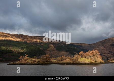 Bella vista sul paesaggio invernale lungo Loch Leven verso montagne innevate in lontananza con il cielo drammatico Foto Stock