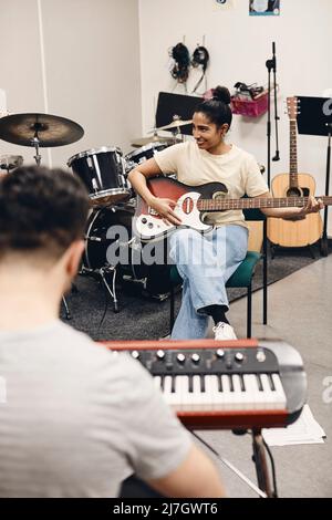 Donna sorridente che pratica la chitarra mentre si prova con l'uomo in classe Foto Stock