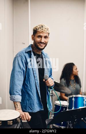 Ritratto di giovane artista sorridente che tiene il microfono in piedi in aula Foto Stock