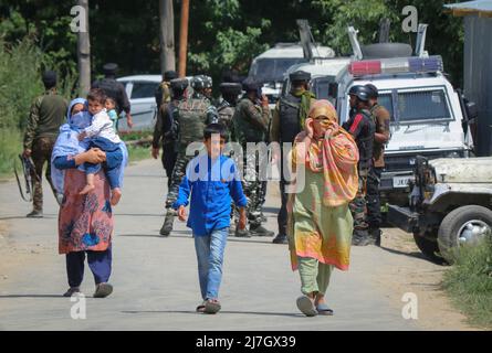 Srinagar, India. 09th maggio 2022. Le donne di Kashmiri con i loro figli camminano davanti ai soldati paramilitari indiani in piedi in guardia nel luogo di un incontro che secondo i media locali scoppiò tra i militanti e le forze governative indiane nella zona di Heff Shirmal del distretto di Shopian. L'agenzia di stampa locale ha riferito che una squadra di forze indiane si avvicinò al punto sospetto, militanti sparati su di loro, quindi scatenando un incontro. (Foto di Faisal Bashir/SOPA Images/Sipa USA) Credit: Sipa USA/Alamy Live News Foto Stock