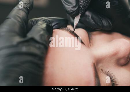 Cosmetologo che applica permanente compongono le sopracciglia per un cliente Foto Stock