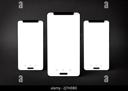 Mockup di tre smartphone isolati su sfondo nero testurizzato con ombre Foto Stock