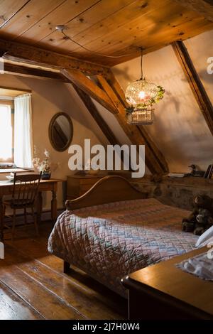 Letto matrimoniale con scrivania in legno e sedia in camera da letto all'interno della vecchia casa 1746. Foto Stock