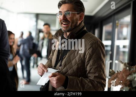 Un uomo d'affari felice che mostra la carta d'identità al centro conferenze Foto Stock