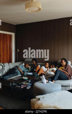 La famiglia si rilassa sul divano nel soggiorno di casa Foto Stock